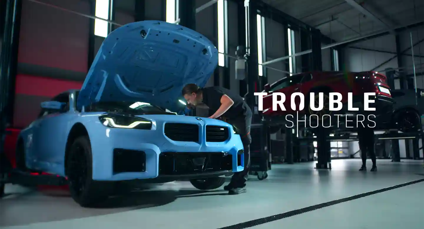 Herobanner Troubleshooters page Mechanic shining a light into an M5, inspecting the engine for any issues. Detailed checks are essential for high-performance vehicles like the M5.